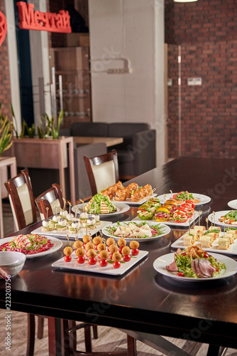 The table is full of delicious snacks, sandwiches, salad and other delicacies. Translation of the word-decor in the background: dream. A festive table in a cafe, restaurant.