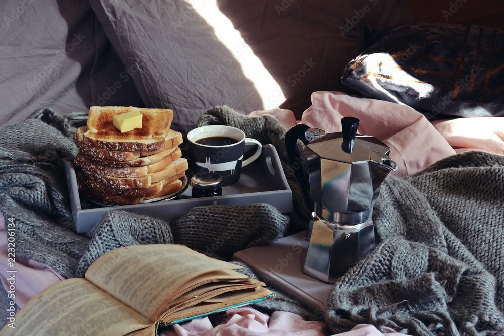 Cozy home with cup of coffee with blanket and book. Hygge home interior. Hygge style breakfast in bed 