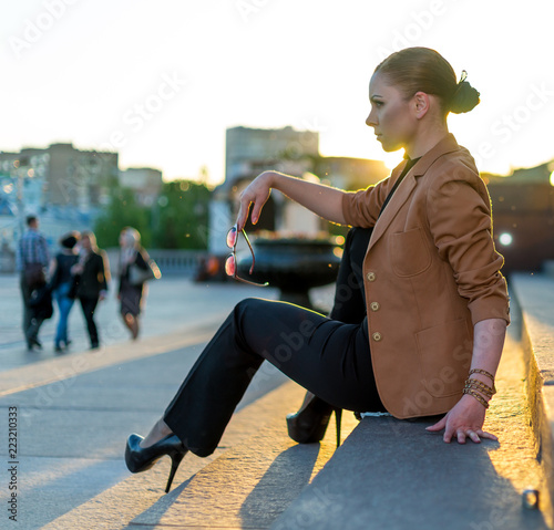 Beautiful young girl in black walks around the spring city photo