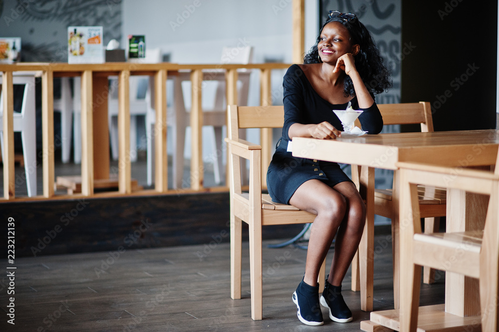 Fototapeta premium African american girl sitting at cafe and eating ice cream.