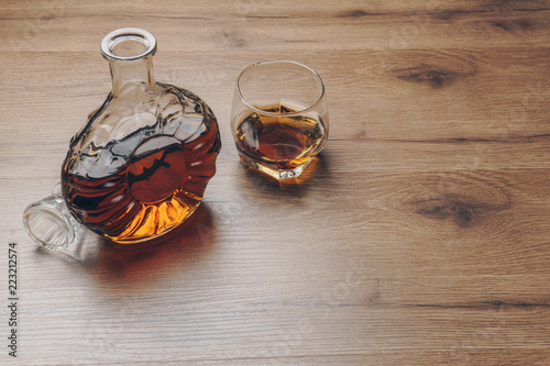 a glass of bourbon whiskey and a whiskey decanter on the wooden table