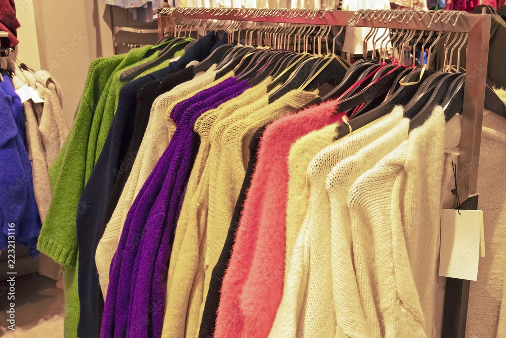 colorful bright pullover hoodies and sweaters hang on hangers in store
