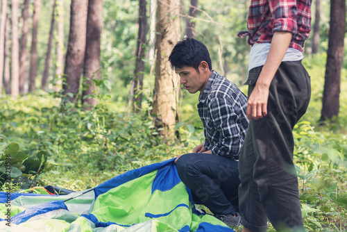 Young Asian travelers camping and setting up tents for overnight in the forest