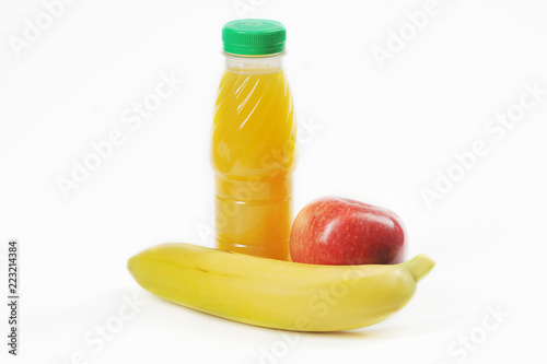 Banana, apple and bottle with juice on a white background. Breakfast for the schoolboy or snacks on the road. Close-up.