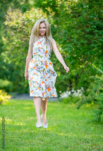Beautiful young girl in a dress walking in the summer Park