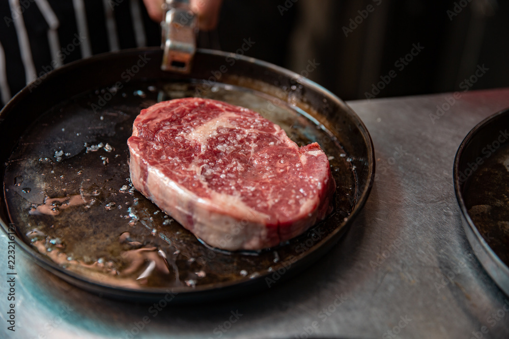Raw meat Ribeye steak with a large salt on cast iron frying pan Raw meat Ribeye steak with a large salt on cast iron frying pan