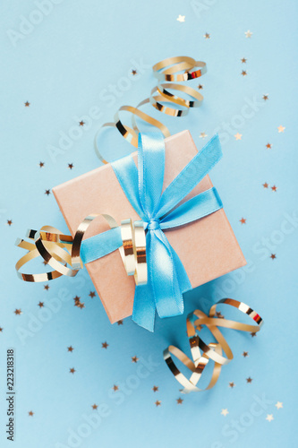 Christmas gift box with golden decorations and sparkles on blue bacground. Gi...