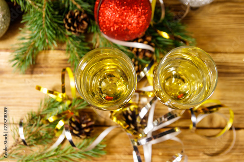 Two glasses of champagne and festive Christmas decorations on wooden table. Christmas and New Year celebration