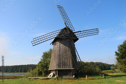 Old wooden windmill on a green field in nature