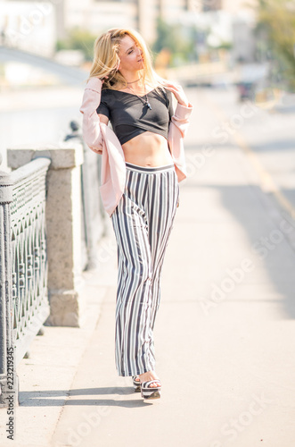 Beautiful young girl in a suit walking around the summer city