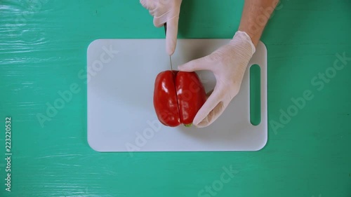 man using knife and cutting board to chop fruit. he removes core and the seeds from plant. photo