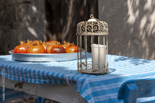 Authentic candle lantern and pommegranades in metal tray on blue and white stiped cotton table cloth at Tenedos (Bozcaada) Island by Aegean Sea