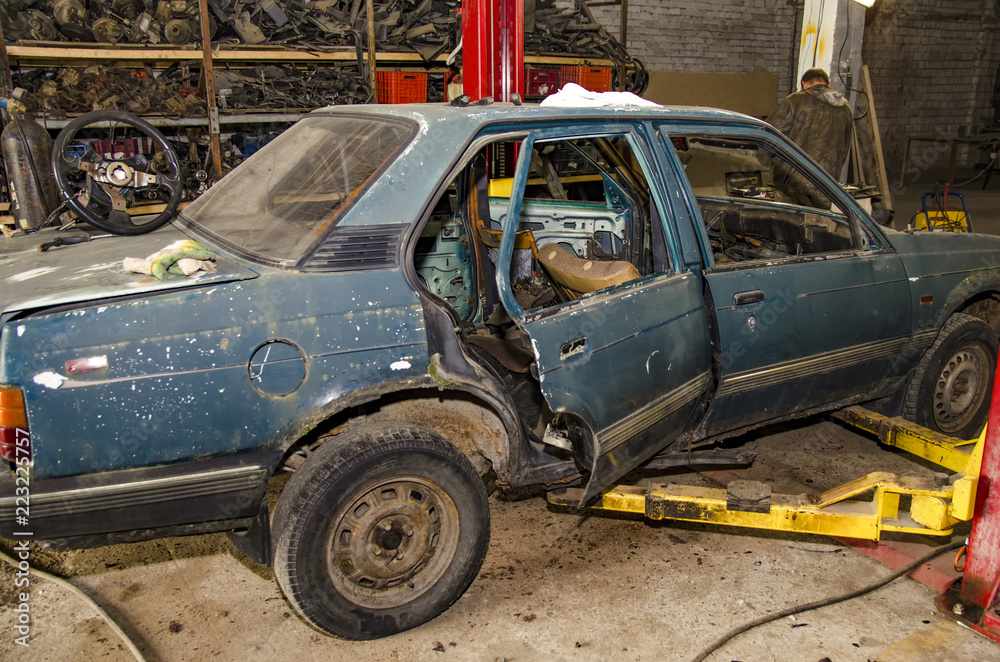Car crash aftermath. Wrecked car waiting to be recycled and dismantled at metal recycling facility.