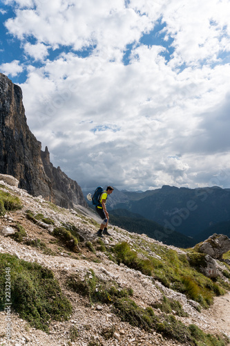 young male mountain climber with an injured knee hikes down the mountain side after a climb in the Italian Dolomites
