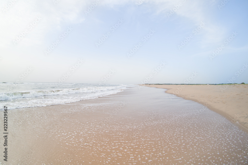 empty beach in pondicherry chennai at sunrise with clouds, waves, surf and reflections. Amazing travel places in India for vacation holidays