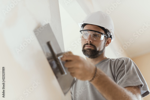 Professional craftsman applying plaster with a trowel photo