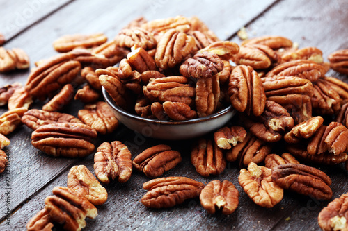 Pecan nuts on a rustic wooden table and pecan nuts in bowl photo