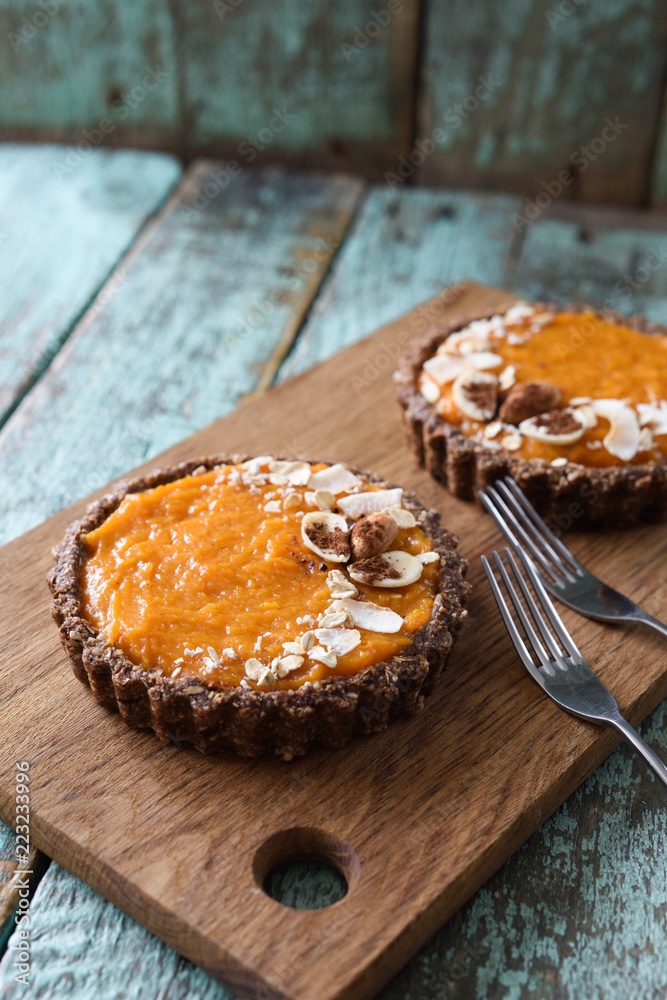 Healthy raw food dessert. Homemade open pies with almond crust and pumpkin cream filling on wooden cutting board copyspace Healthy raw food dessert. Homemade open pies with almond crust and pumpkin cream filling on wooden cutting board copyspace