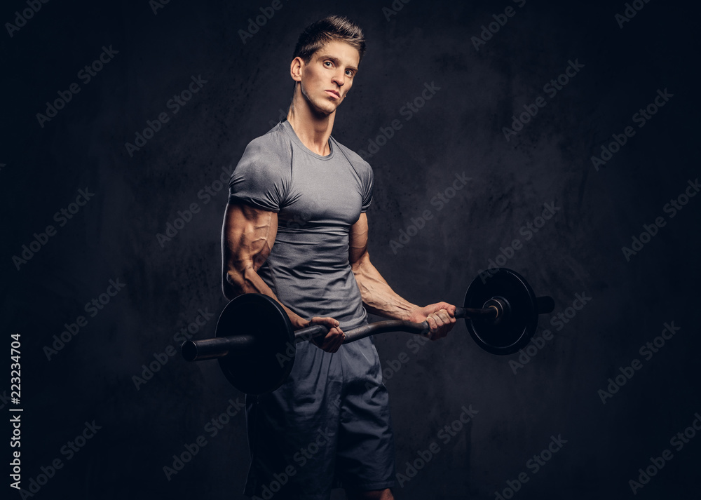 Φωτογραφία Handsome sportsman with stylish hair dressed in a sportswear doing the exercises with the barbell