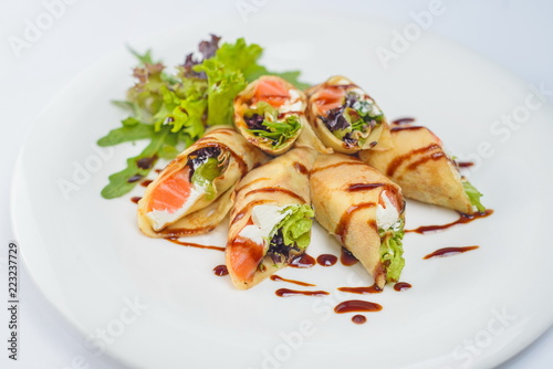 pancakes with salmon and cheese on a white plate