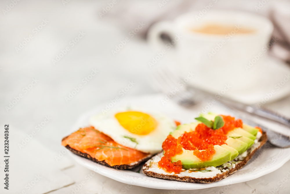 Avocado and red caviar, smoked salmon and fried egg rye toasts for breakfast, close up Avocado and red caviar, smoked salmon and fried egg rye toasts for breakfast, close up