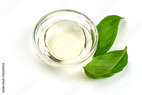 Vinegar in glass bowl with basil leaves, isolated on white background