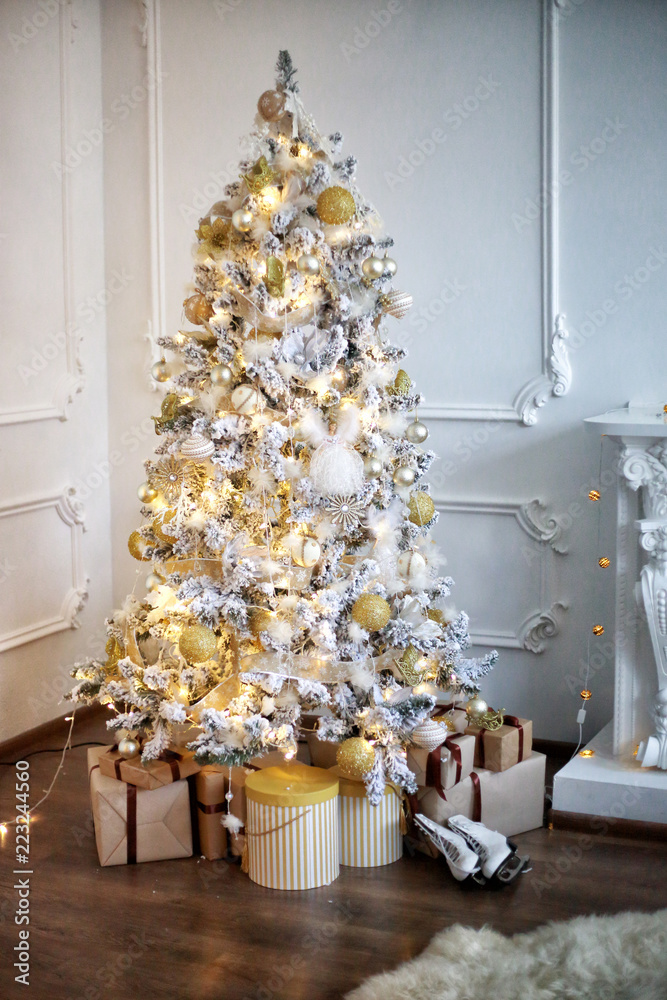 New Year's tree with gifts and toys in a white room with a fireplace New Year's tree with gifts and toys in a white room with a fireplace