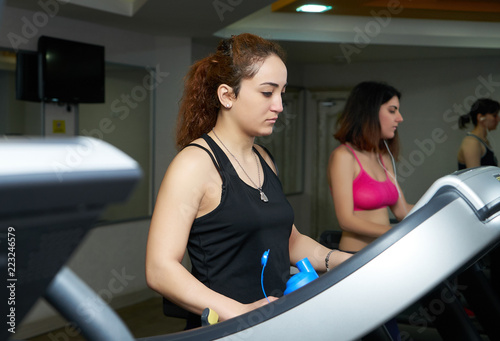 Side view of attractive sports women on running track. Girls on treadmill in gym fitness room