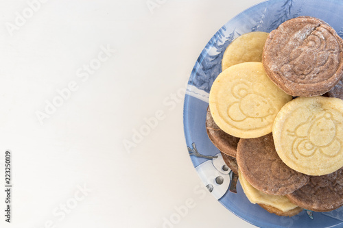 Home made Christmas vanila and cacao buiscuits on a blue bowl with winter decoration and with white background and space to write something. photo