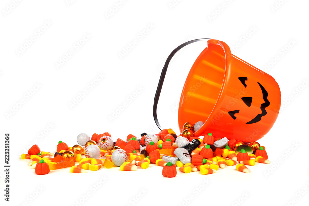 Fototapeta premium Spilling Halloween Jack o Lantern candy collector with a pile of candy over a white background