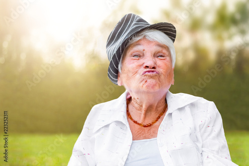 beautiful old lady in a hat pulled her lips, wants to kiss, outdoors