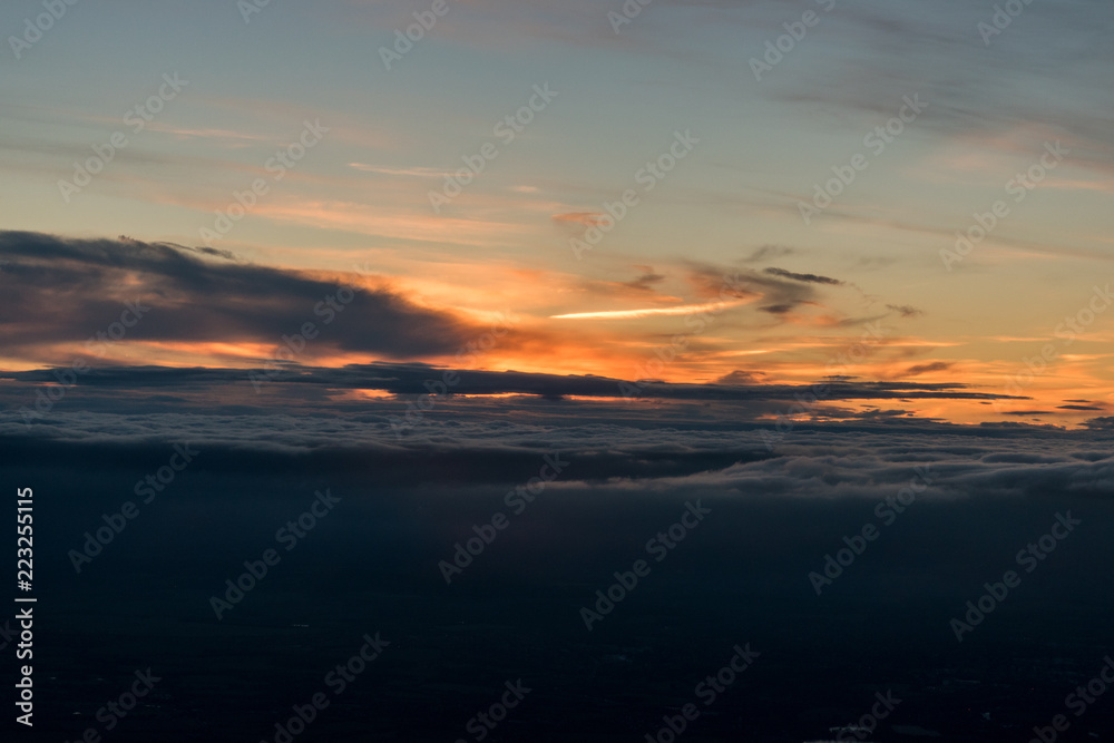 View from plane on the orange sky, sunset sun and clouds