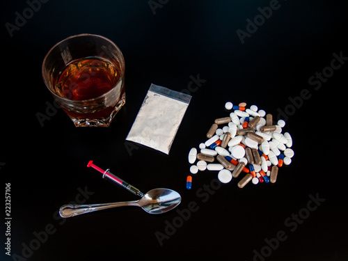 Foto Pills of different sizes, shapes and colors, a glass of whiskey, drugs and syrin
