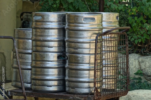 a pile of gray metal barrels on an old wheelbarrow on the street © butus