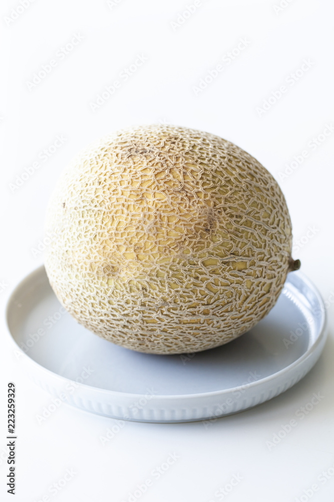 Cantaloupe or melon sitting on blue plate on white background Cantaloupe or melon sitting on blue plate on white background