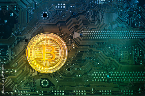 Gold bitcoin coin on a colorful circuit board. Blue-green background