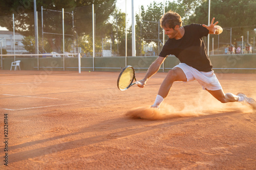 Professional tennis player man playing on court in afternoon. © pablobenii