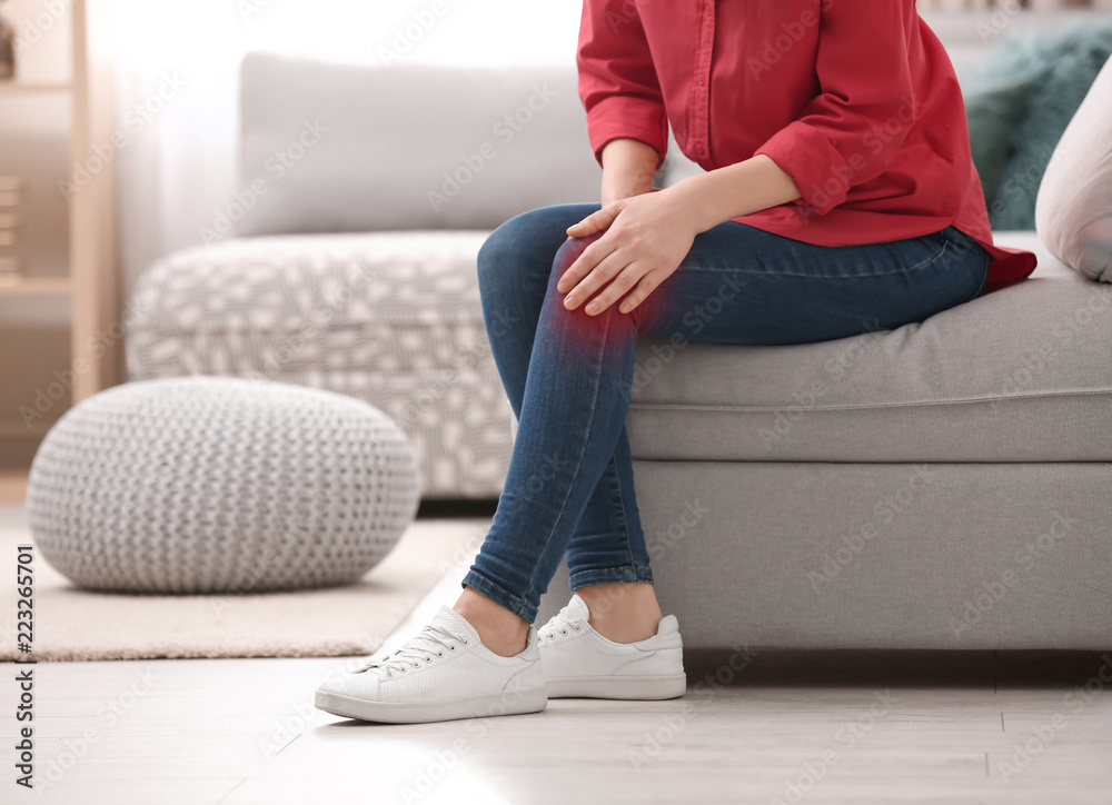 Young woman suffering from knee pain at home Young woman suffering from knee pain at home