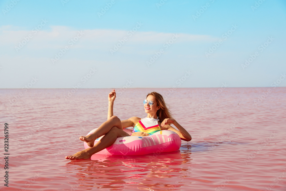 Beautiful woman on inflatable ring in pink lake Beautiful woman on inflatable ring in pink lake