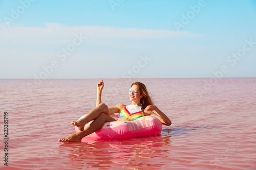 Beautiful woman on inflatable ring in pink lake