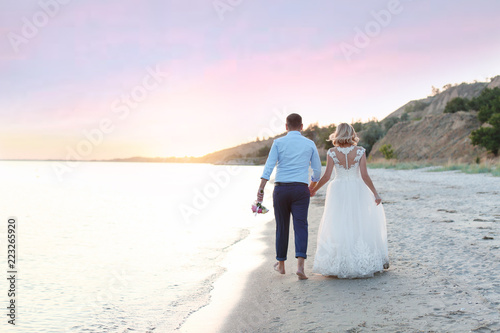 Wedding couple walking on beach. Space for text