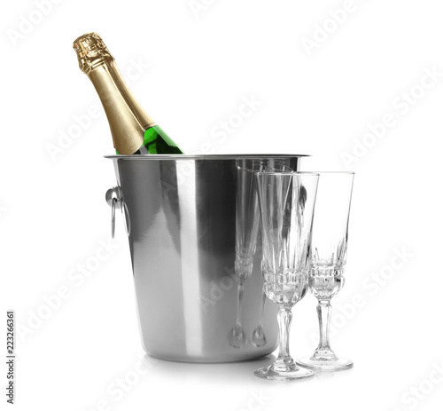 Bottle of champagne in bucket and glasses on white background