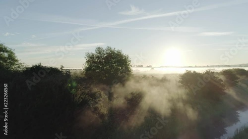 Slowly sliding towards the morning sun shining through the trees in a misty field in Otmoor, Oxfordshire. photo