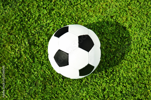 Soccer ball on fresh green football field grass, top view