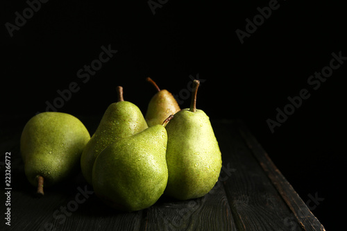 Ripe pears on wooden table against dark background. Space for text