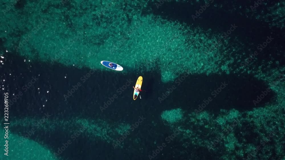 Video from above, aerial view of  two people on a stand up paddle (SUP) in Sardinia, Italy.