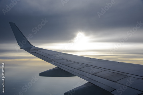 Airplane wing in the sky against the background of atmospheric air, dawn and clouds