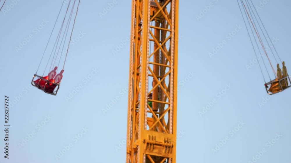 African American couple suspended on a swing on a spinning thrill ride in slow motion on a sunny day at a county fair