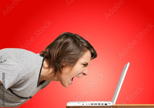 Furious young man screaming on laptop