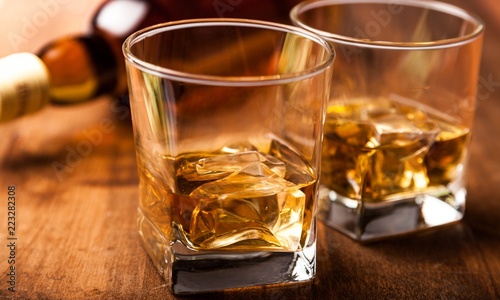 Fototapeta Naklejka Na Ścianę i Meble -  Glasses of Whiskey and Ice with Bottle on Background